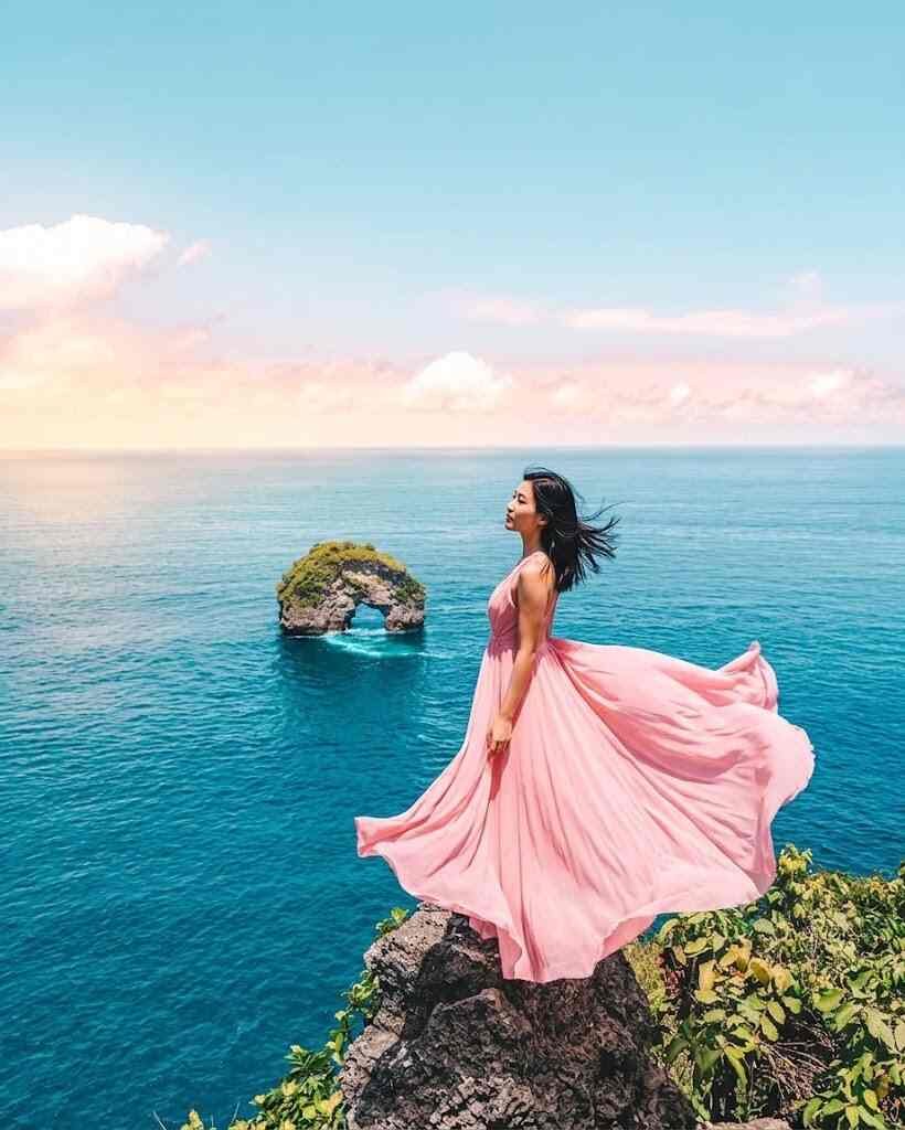 Panoramic view of towering white limestone cliffs and a rock arch in the ocean at Banah Cliff Nusa Penida.