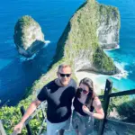 A tourist couple taking a photo at the Kelingking Beach cliff while joining a Nusa Penida Tour with NPT.