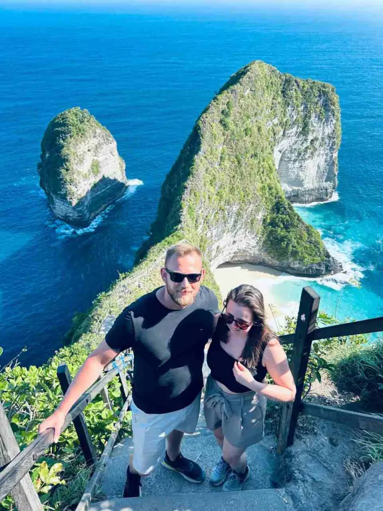 A tourist couple taking a photo at the Kelingking Beach cliff while joining a Nusa Penida Tour with NPT.